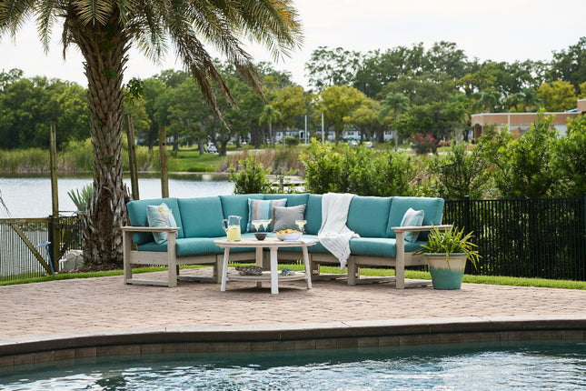 Turquoise outdoor sofa set on a wooden deck by a pool with a scenic background.