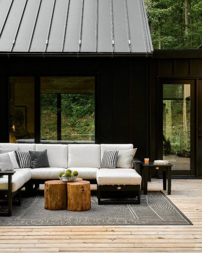 Outdoor patio area with a modern house, furniture, and greenery.